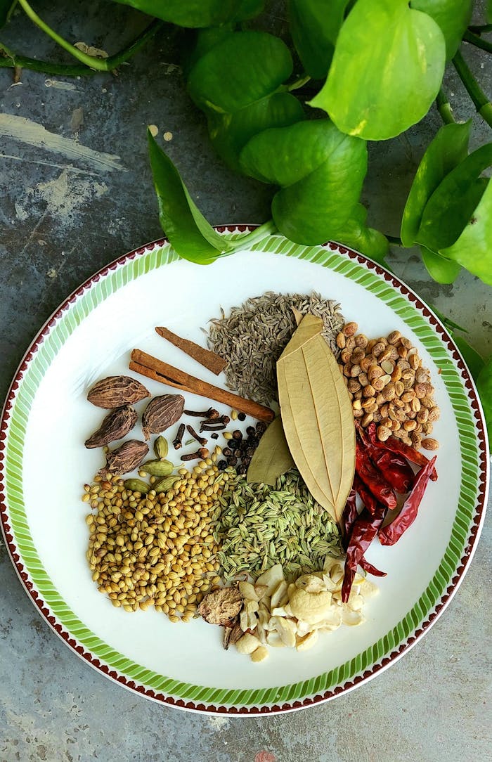 Colorful assortment of spices displayed on a plate with green leaf background.