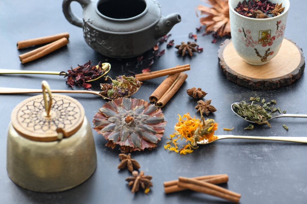 Flat lay of teapot, teacup, and assorted herbs and spices on a table.